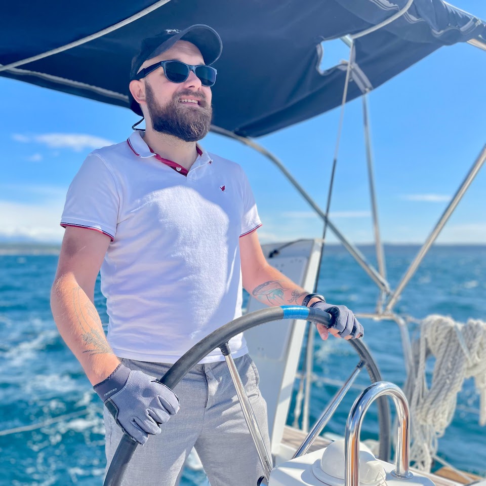 Portrait photo of Krzysztof Adam Witalewski steering a yacht